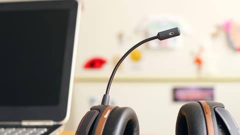 A headset resting beside a laptop on a desk